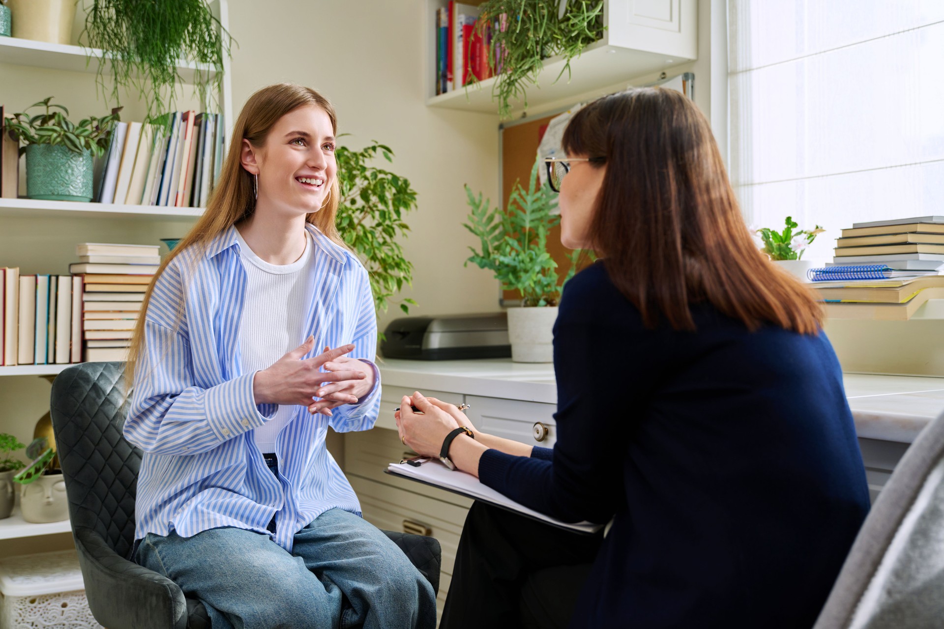 Smiling young teenage female patient talking to professional mental therapist